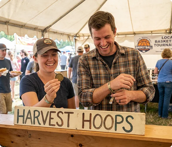 Visitors smiling and browsing Harvest Hoops keepsakes inside the tent